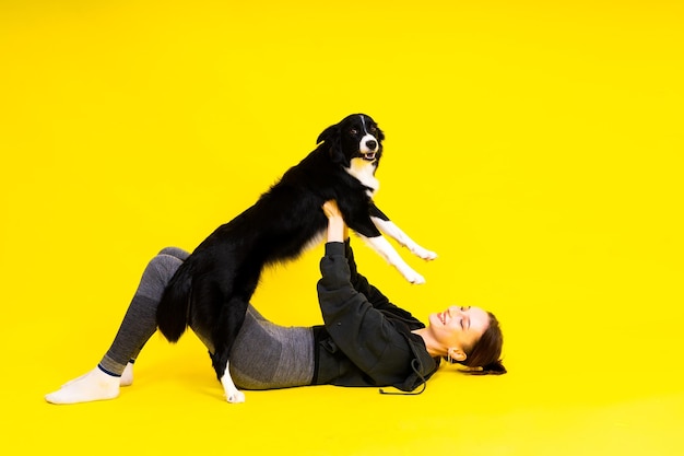 Shot of a sport female in leggings with a border collie dog isolated on yellow and red background