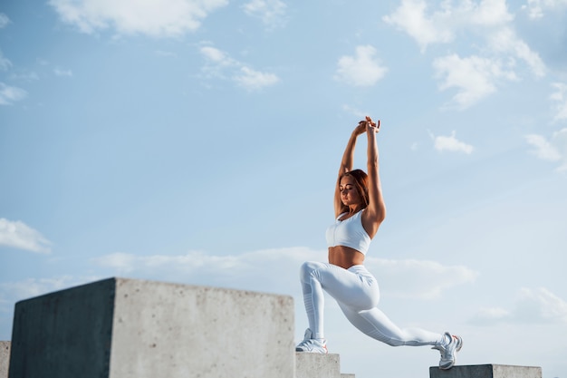 Shot of sportive woman doing fitness exercises near the lake at daytime