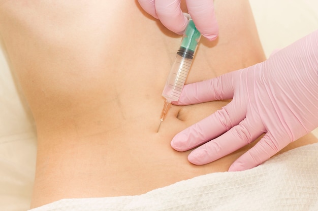 A shot in the stomach. A woman at a cosmetologist receives lipolytics in the stomach. Fat-burning