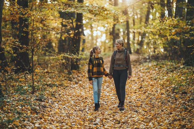 Shot of a teen girl and her mom walking together through the forest in autumn.