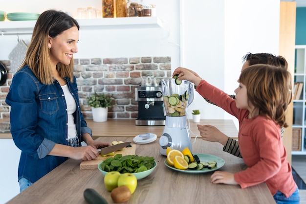 Shot of two boys helping his mother to prepare a detox juice with blender in the kitchen at home.