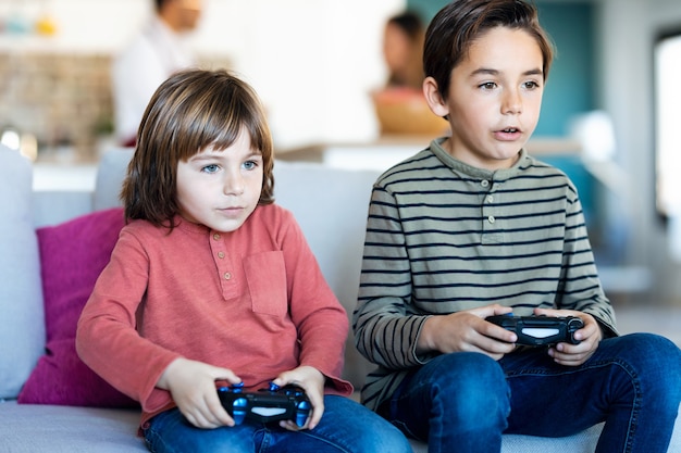 Shot of two nice brothers playing video games while sitting on the sofa at home.