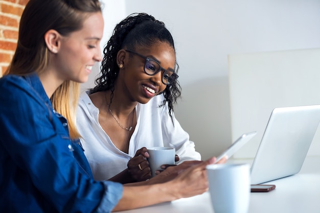 Shot of two pretty young business women working together with digital tablet in the office.