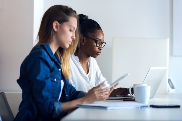 Shot of two pretty young business women working with digital tablet and laptop in the office.