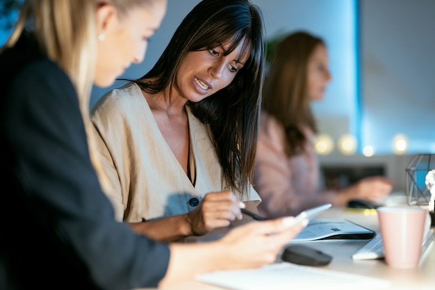 Shot of two smart business women working together with digital tablet while talking in the office.