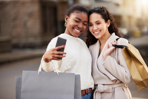 Shot of two young women taking selfies while shopping against an urban background