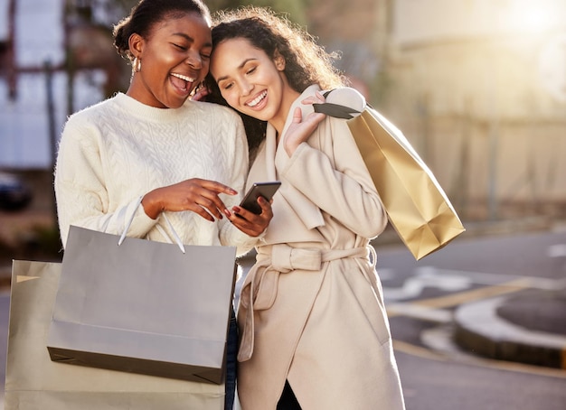 Shot of two young women using a smartphone while shopping against an urban background