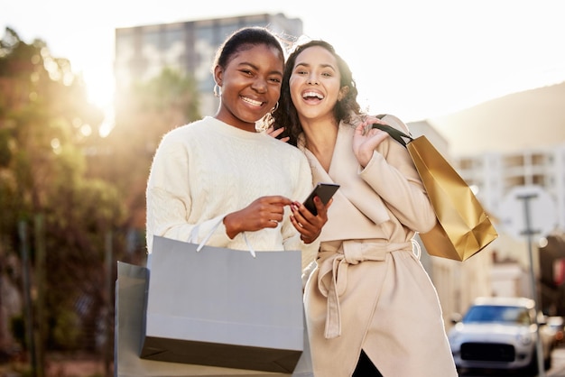 Shot of two young women using a smartphone while shopping against an urban background