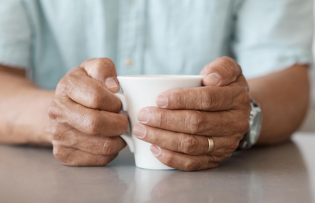 Shot of an unrecognizable man drinking a cup of coffee at home