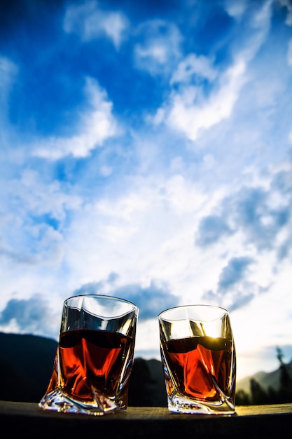 Shot of whiskey at sunset dramatic sky on mountain landscape background