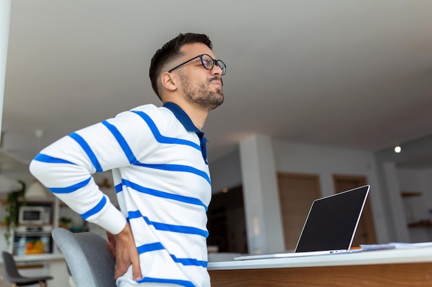 Shot of a young businessman suffering from a backache while working at his desk in his office