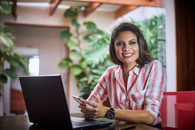 Shot of a young Caucasian girl from Brazil with a laptop and smartphone