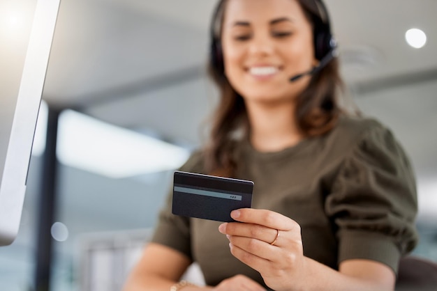 Shot of a young female call center agent holding a credit card at work