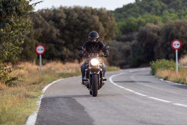 Shot of young man biker having fun driving the empty highway on a motorcycle tour journey.