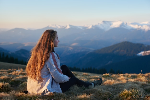 Shot of a young woman sitting on top of a mountain