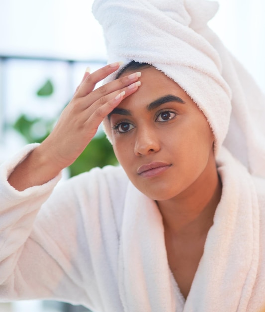 Should I be worried about wrinkles too Shot of a young woman looking at her face in a bathroom mirror at home