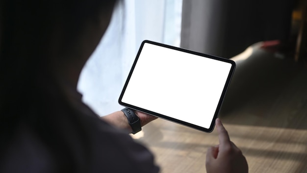 Over shoulder closeup view of woman using digital tablet in living room