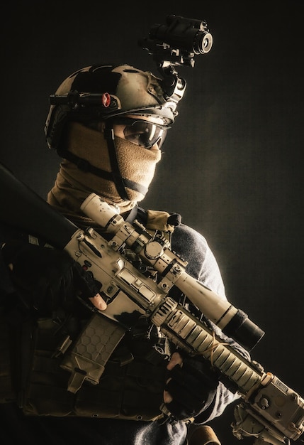 Shoulder portrait of army elite troops sniper antiterrorist tactical team marksman wearing helmet with thermal imager hiding face behind mask armed rifle with optical scope studio shoot on black