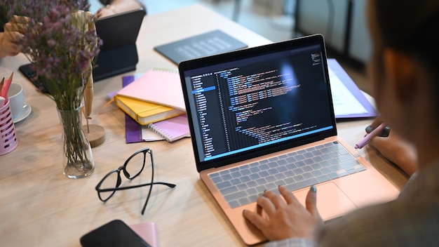 Over shoulder view of software developers programming on desktop computer in startup office