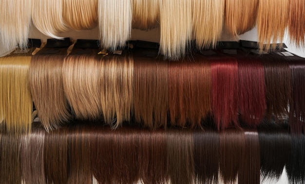 Showcase of natural looking wigs in different colors in beauty salon variation shades of hair on shelf in wig shop