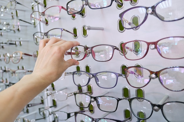 Showcase with glasses in the store, hand choosing glasses