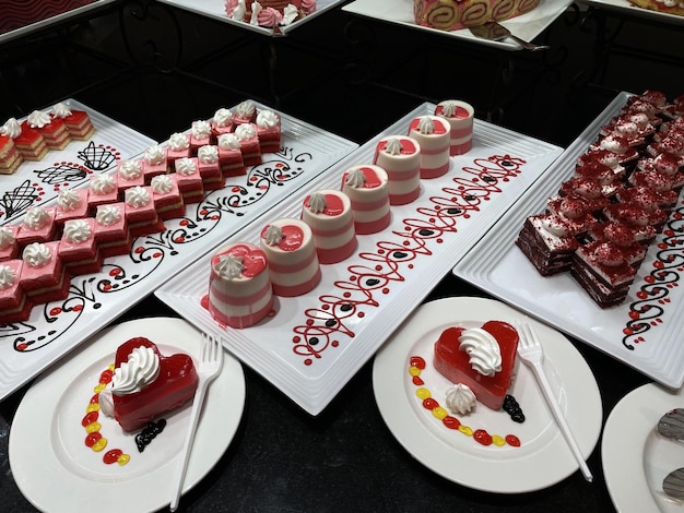 Showcase with sweets Colored sakes on white plates on black table