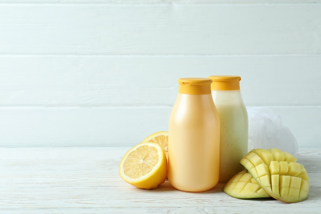 Shower gels, mango and lemon on white wooden background