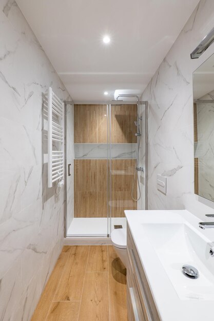 Shower zone with wooden finishing and glass door interior of modern refurbished bathroom