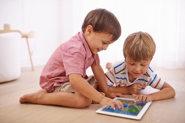 Showing him some tablet tricks Shot of little boys playing on the floor