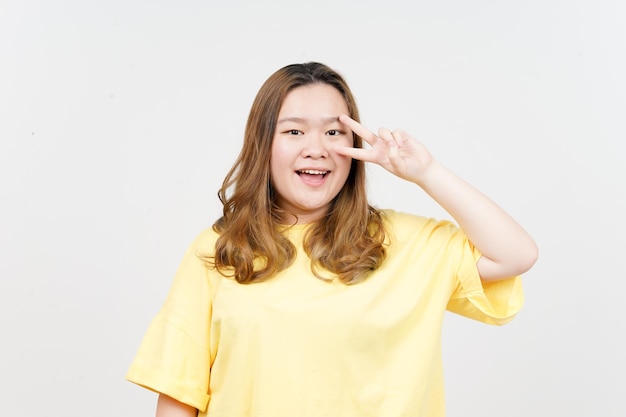 Showing Peace Sign of Beautiful Asian Woman wearing yellow TShirt Isolated On White Background