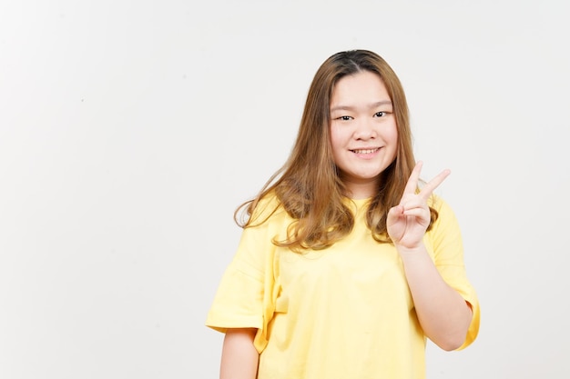 Showing Peace Sign of Beautiful Asian Woman wearing yellow TShirt Isolated On White Background