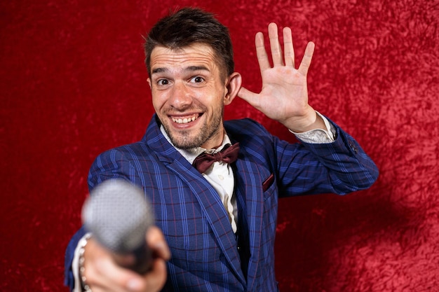 showman showing ear gesture and reaching out microphone while listening during performance