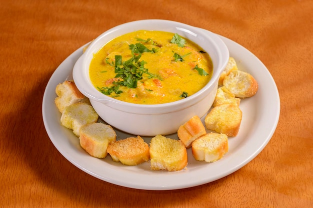 Shrimp broth with toasted bread on a wooden table Traditional Brazilian appetizer