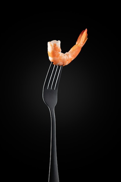 Shrimp on a fork isolated. on black  background Vertical format.