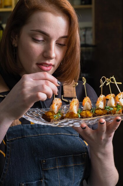 Photo shrimp and mango chutney canapes in female fingers near open mouth mini sandwich eating