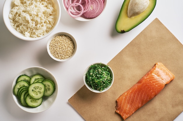 Shrimp salmon poke bowl on craft paper, Chuka Salad, white rice, cucumber