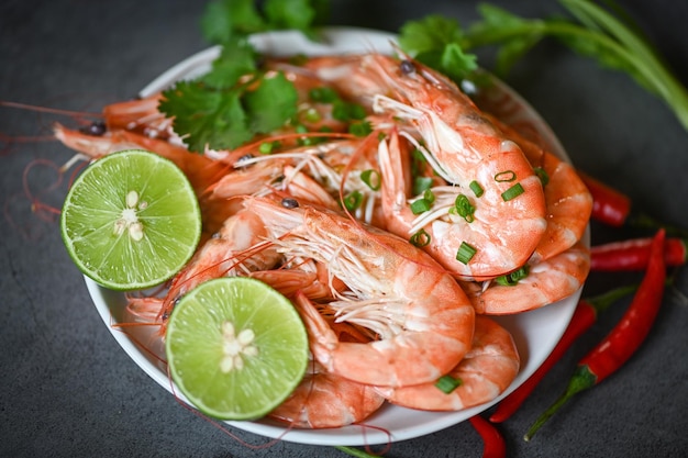 Shrimp on white plate background dining table food Fresh shrimps prawns seafood lemon lime with herbs and spice