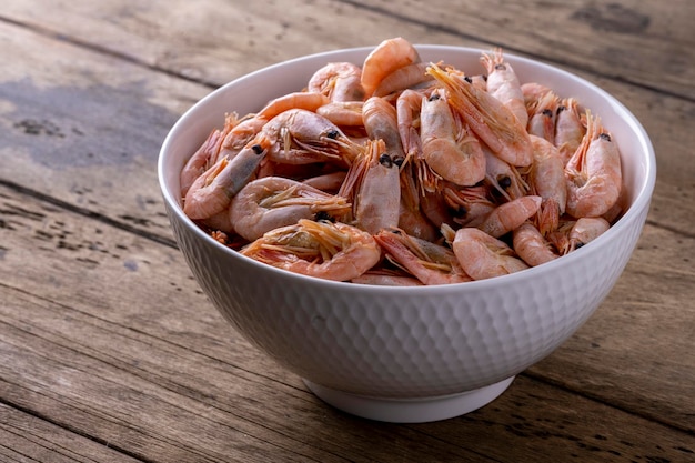 Shrimp in a white plate on a wooden background