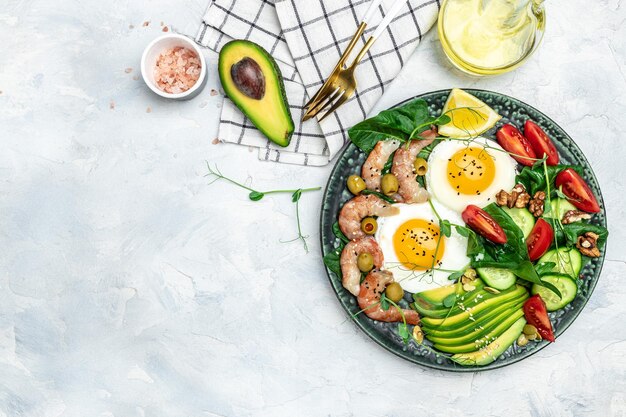 Photo shrimps prawns soft fried egg fresh salad tomatoes cucumbers and avocado on a light background ketogenic diet breakfast keto paleo lunch top view