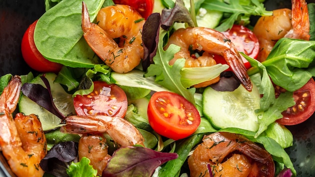 Shrimps salad, cherry tomatoes, cucumber and mixed leaves. Healthy food. Clean eating. Food recipe background. Close up.