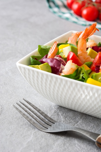 Shrimps salad with mango and avocado on gray stone