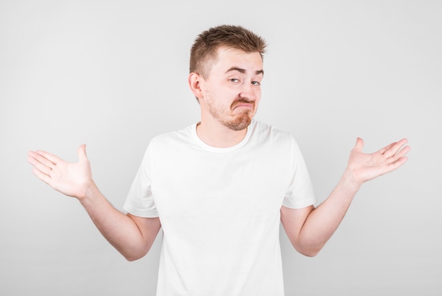 Shrugging man in white t-shirt looking at camera