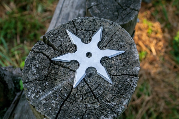 Shuriken throwing star traditional japanese ninja cold weapon stuck in wooden background