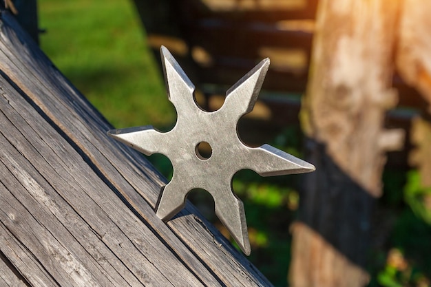 Shuriken throwing star traditional japanese ninja cold weapon stuck in wooden background