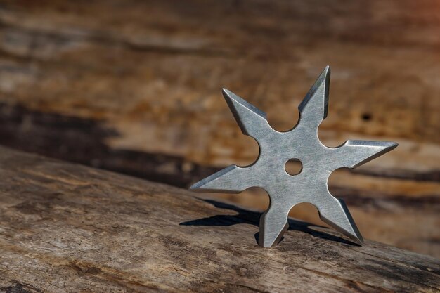 Shuriken throwing star traditional japanese ninja cold weapon stuck in wooden background