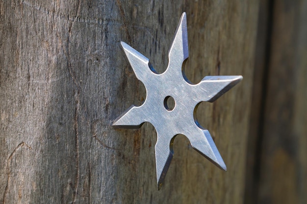 Shuriken throwing star traditional japanese ninja cold weapon stuck in wooden background