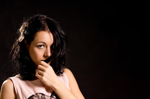 Shy bashful young woman pulling her hair across her face head and shoulders portrait in darkness