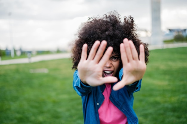 Shy young woman with curly hair trying to avoid being photographed