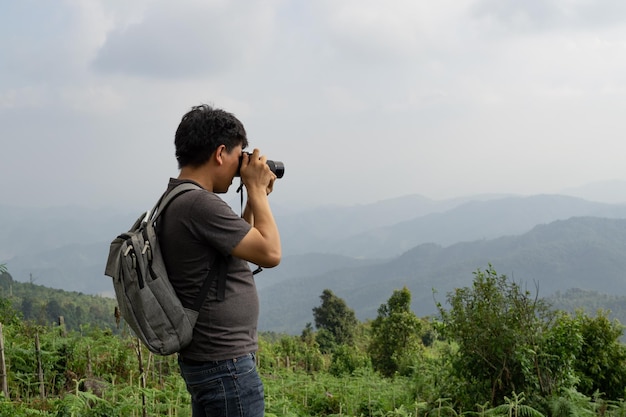 A sian man with his backpack and camera is travel alone and take photo at the country side