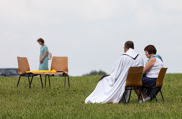 SIAULIAI, LITHUANIA - JUL 28, 2019: Woman confesses during the religious event on the Hill of Crosses. Hill of Crosses is a unique monument of history and religious folk art in Siauliai, Lithuania